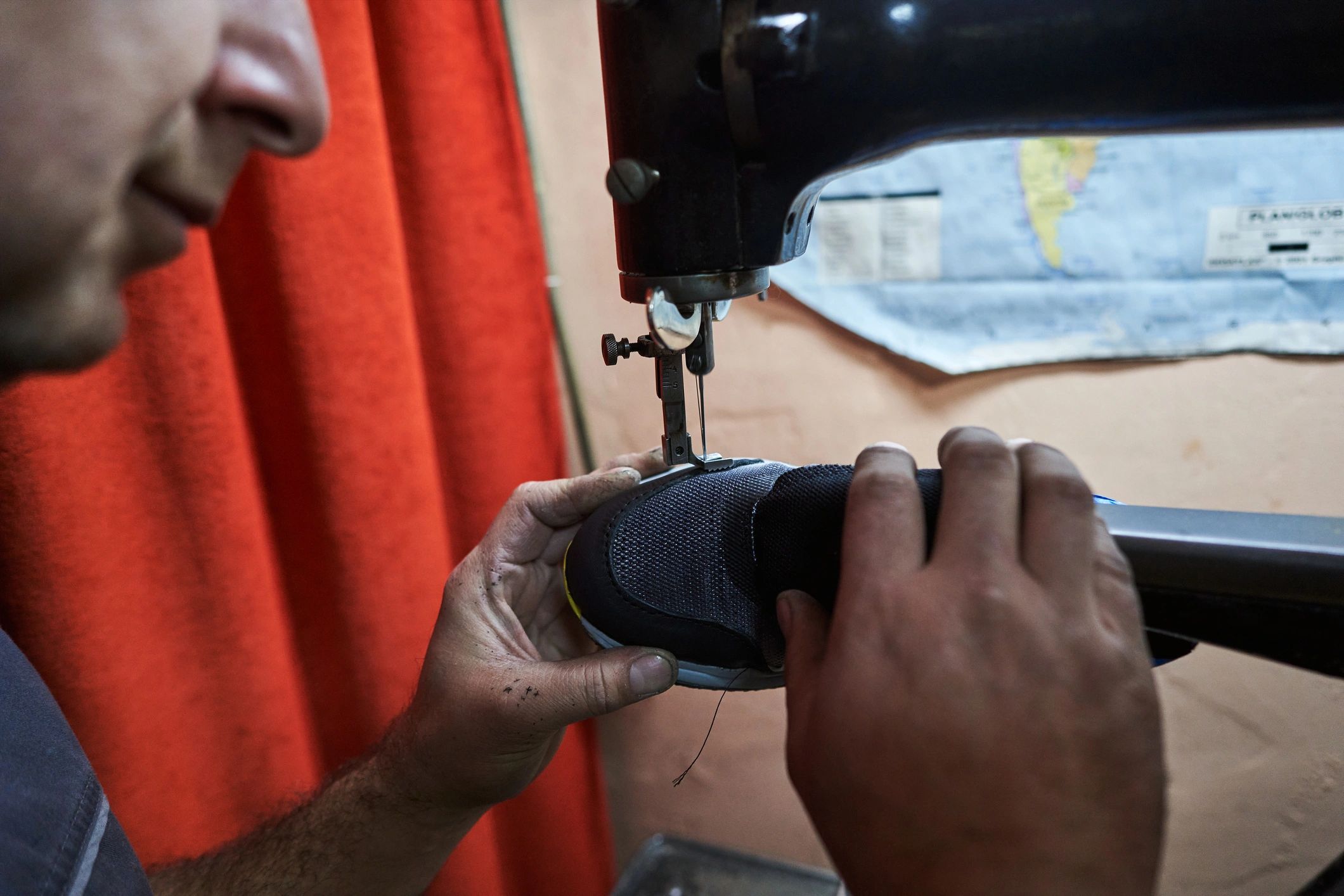 Shoe repair technician sewing a sneaker
